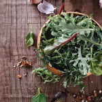 A wooden bowl of organic green leafy vegetables. The thyroid needs very specific foods to maintain proper function.