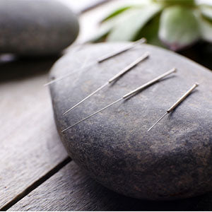 Several acupuncture needles on a rock.