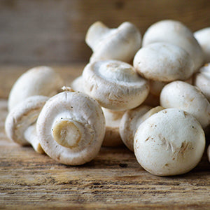 A group of mushrooms piled in a wooden tabletop.