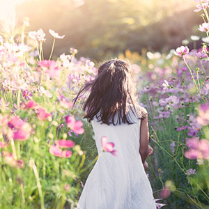 A little girl walking in a field of flowers.