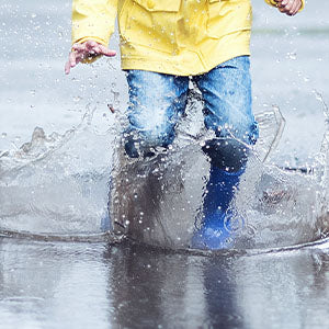 A little boy playing in rain puddles.