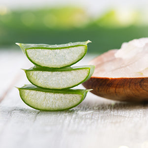 Sliced aloe vera with a wooden bowl in the background.