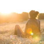 A women sitting in the middle of the field watching the sunset. Sun exposure assists the pineal gland and stimulates the mind.