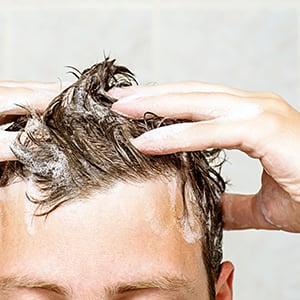 An individual shampooing their hair. Formaldehyde is a dangerous chemical that can be found in shampoos.