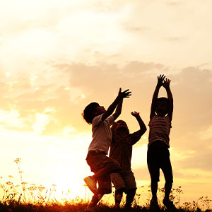 Three little boys playing out in a field.