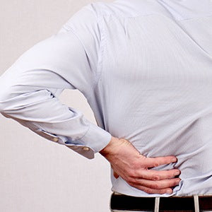 A person holding his lower back area. Most kidney stones pass through the urinary tract with no trouble.