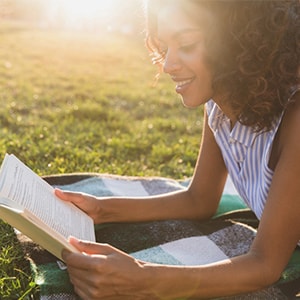 A woman relieving stress by reading in the park. Lithium orotate is another way to manage stress.