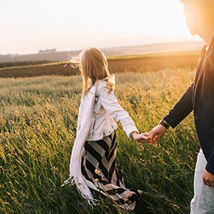 A couple walking through a field together holding hands.