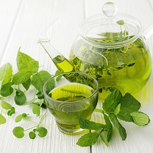 A kettle and cup of green tea. Green tea is a natural metabolism booster.