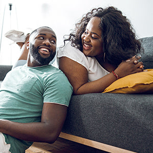 Man and woman on the couch, smiling at each other.