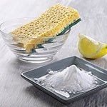 Image of a bowl of water, a lemon wedge, and baking soda. Great ingredients to make your own natural cleaning products.