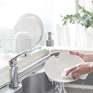 A person washing dishes with organic dishwashing soap.