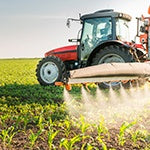 A farmer spreading pesticides on the crops to kill insects, weeds, fungi, and bacteria.