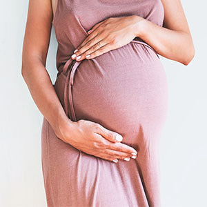 A pregnant woman is holding her stomach. Placenta helps balance the bacteria in your gut.