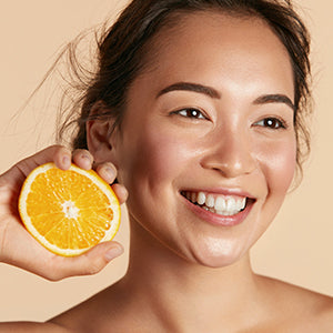 Smiling woman with orange in her hand.